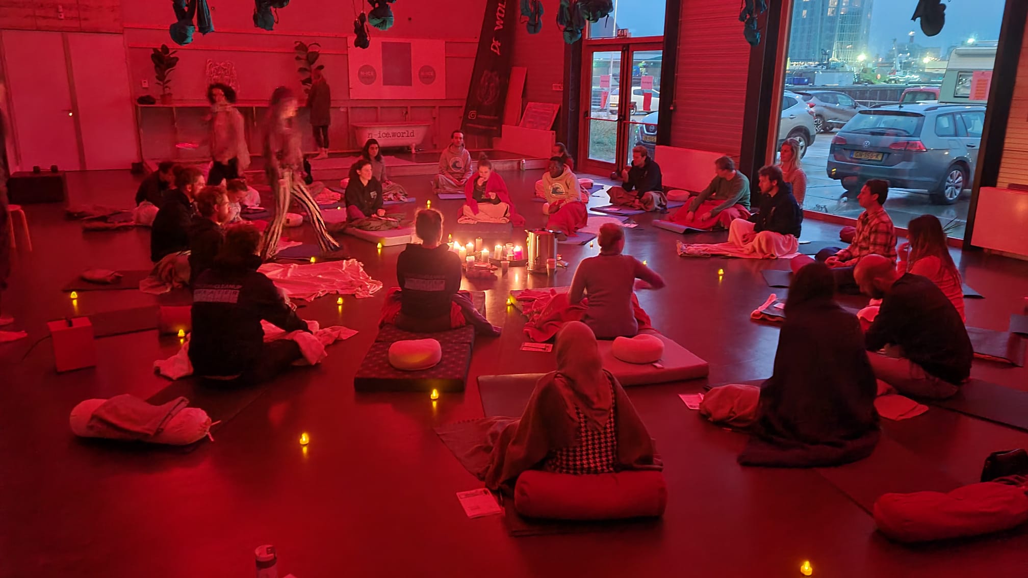 Groep deelnemers zit in cirkel rond kaarsen na afloop van een No Escape Room bij n-ice.world