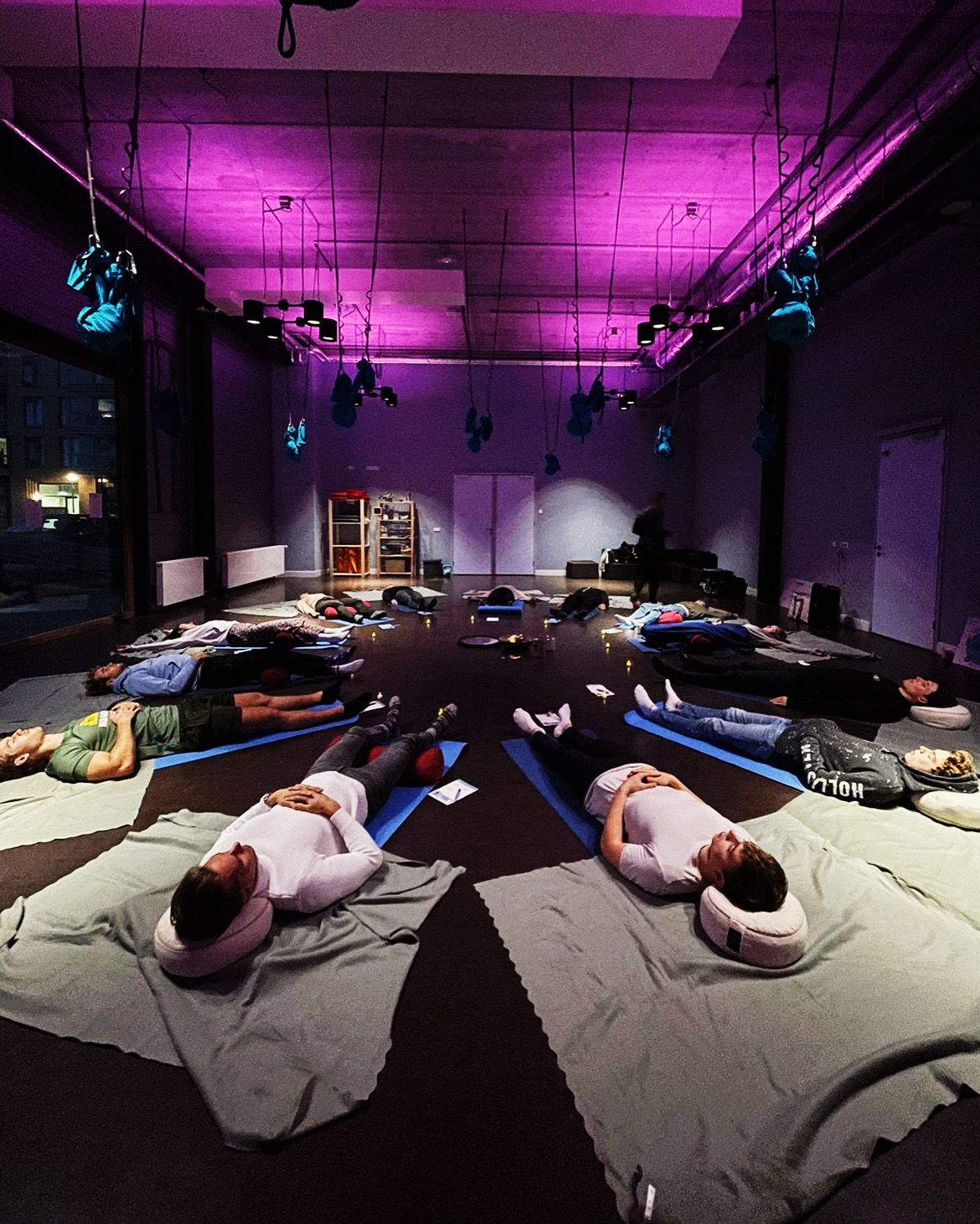 Deelnemers liggen in symmetrische V-opstelling tijdens een No Escape Room sessie, immersive paarse verlichting